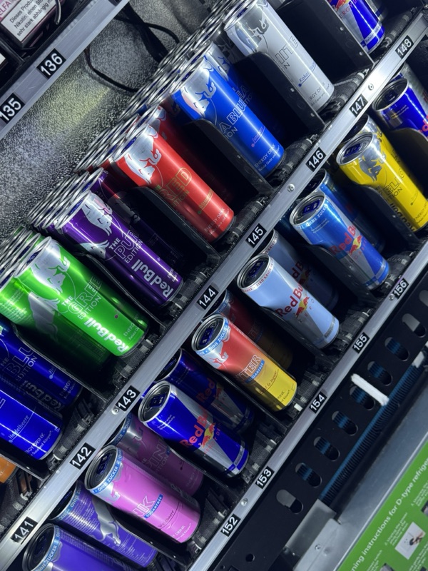 Bunte Energydrink-Dosen dicht an dicht in den nummerierten Spiralen eines Automaten