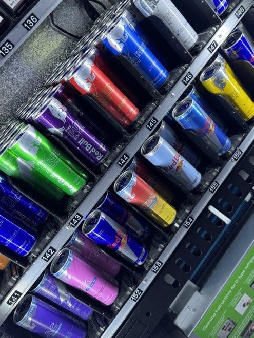 Energydrink- und Getränkedosen in den Spiralen eines gekühlten Automatenfachs