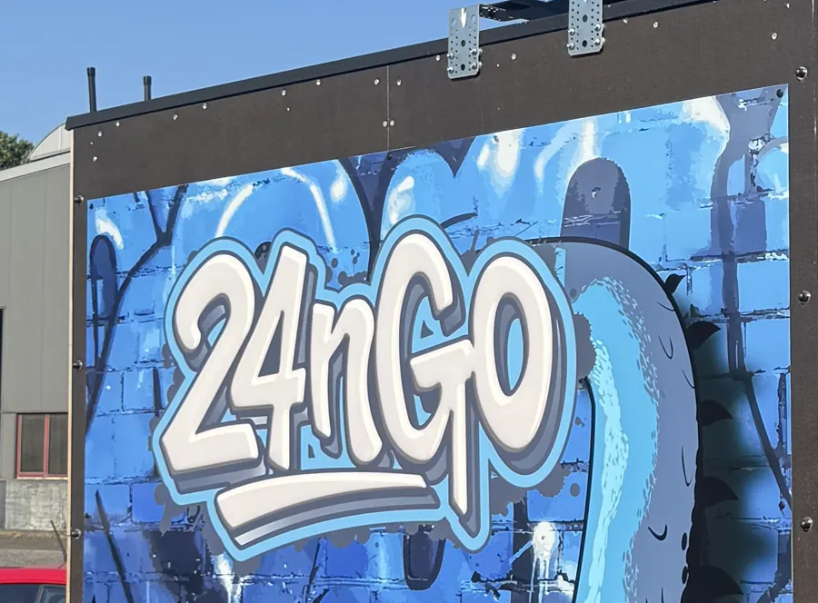 Der 24nGo-Schriftzug als blaues Graffiti auf der Wand eines mobilen Containers