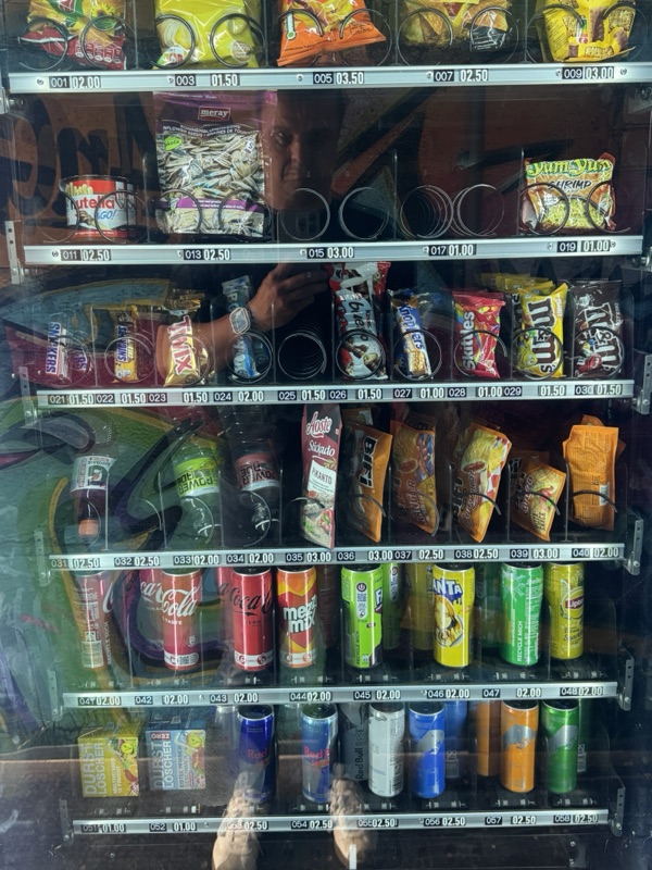 Ein Kunde greift in den Ausgabeschacht eines vollen Getränkeautomaten