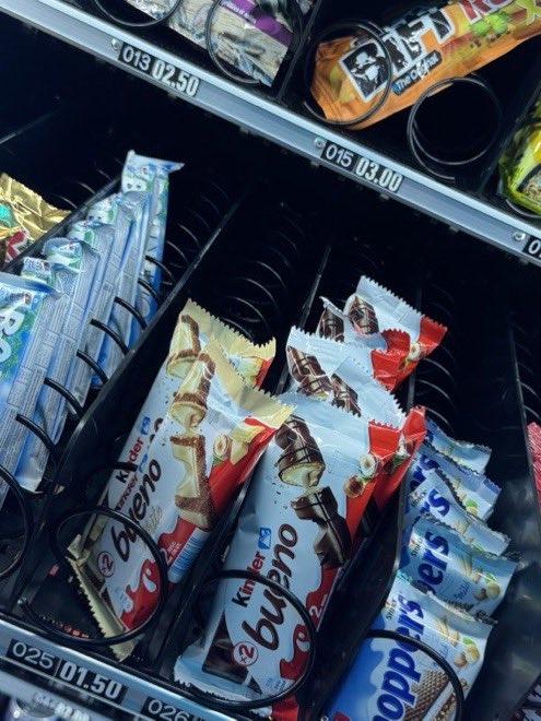 Schokoriegel und Waffeln in den Spiralen eines Automaten, darunter die Preisschilder