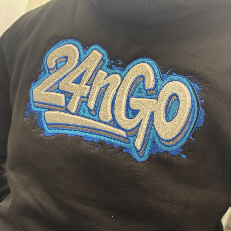 Gestickter 24nGo-Schriftzug in Blau und Weiß auf einem schwarzen Shirt