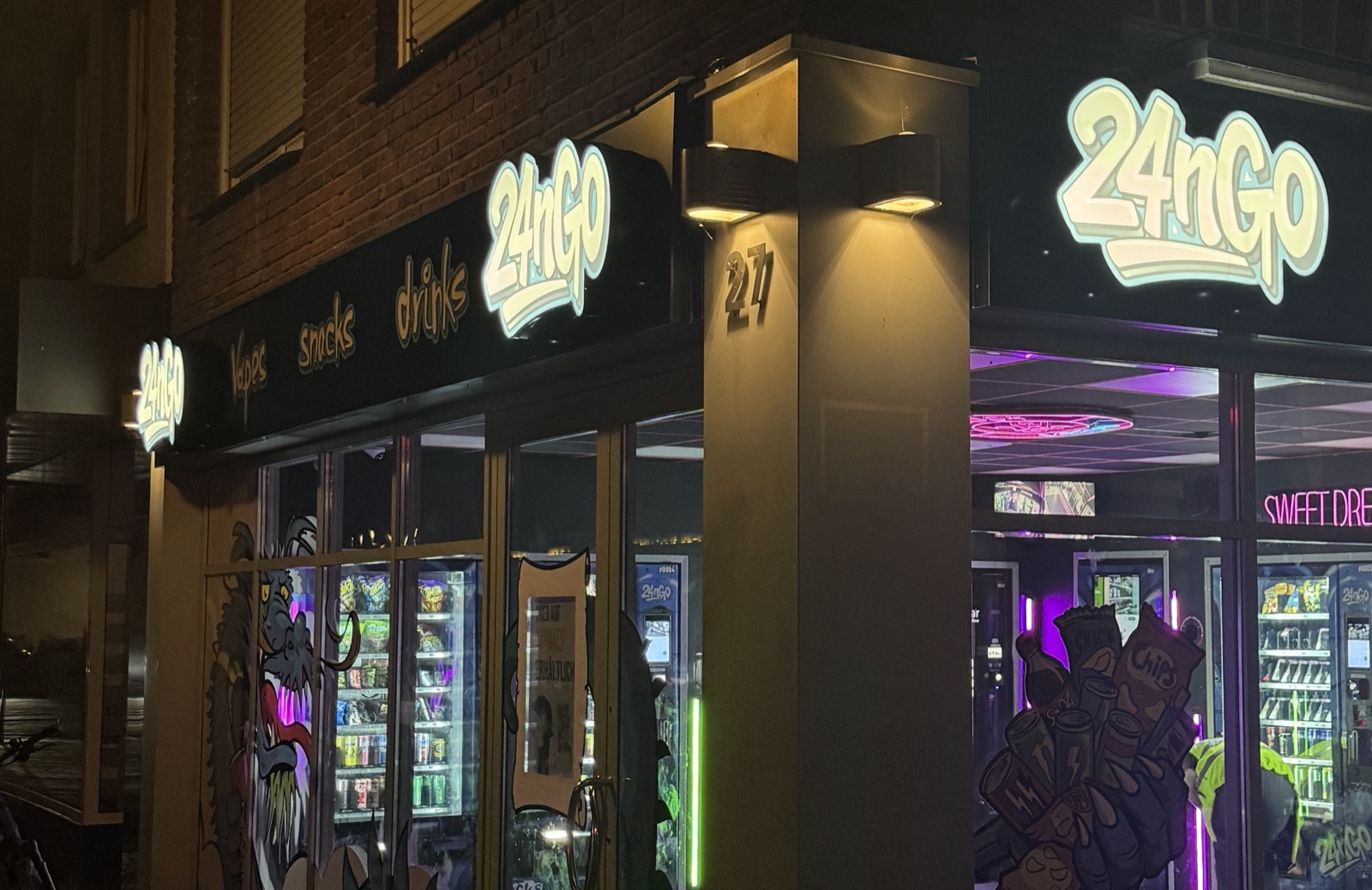 Der 24nGo-Store an der Wüllener Straße in Vreden bei Nacht: leuchtender Schriftzug über der Ecke, dahinter hell erleuchtete Automaten in violettem Licht